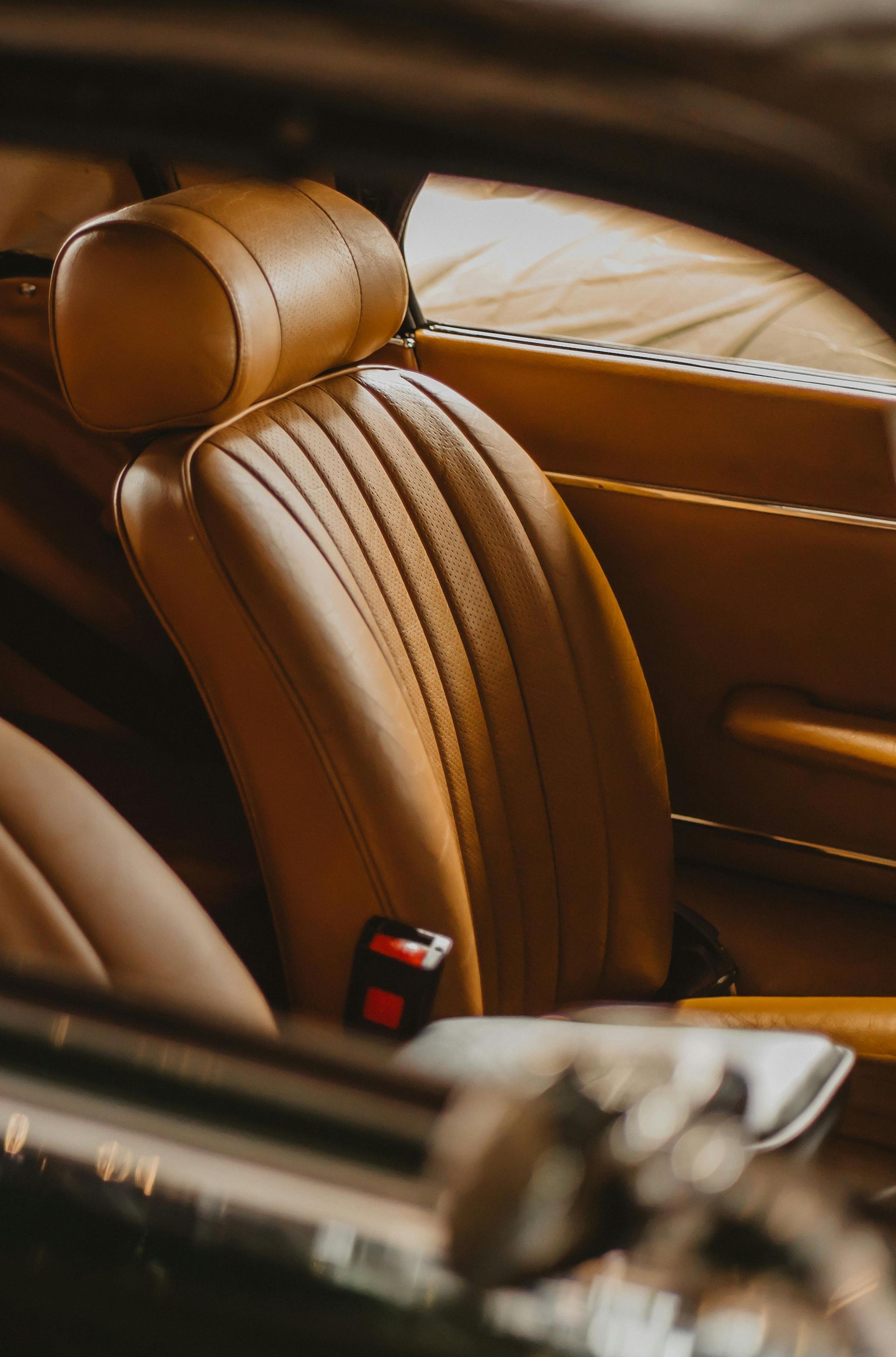 Tan leather car seat with vertical stitching.