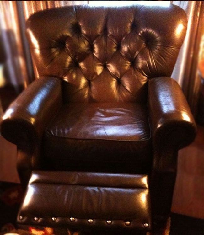 Brown leather recliner chair with tufted back and footrest extended.