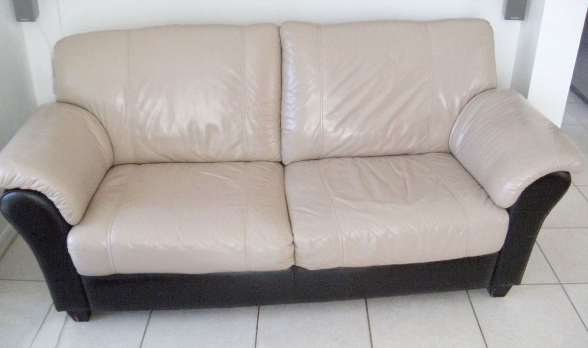 Two-seater beige leather sofa with black sides.