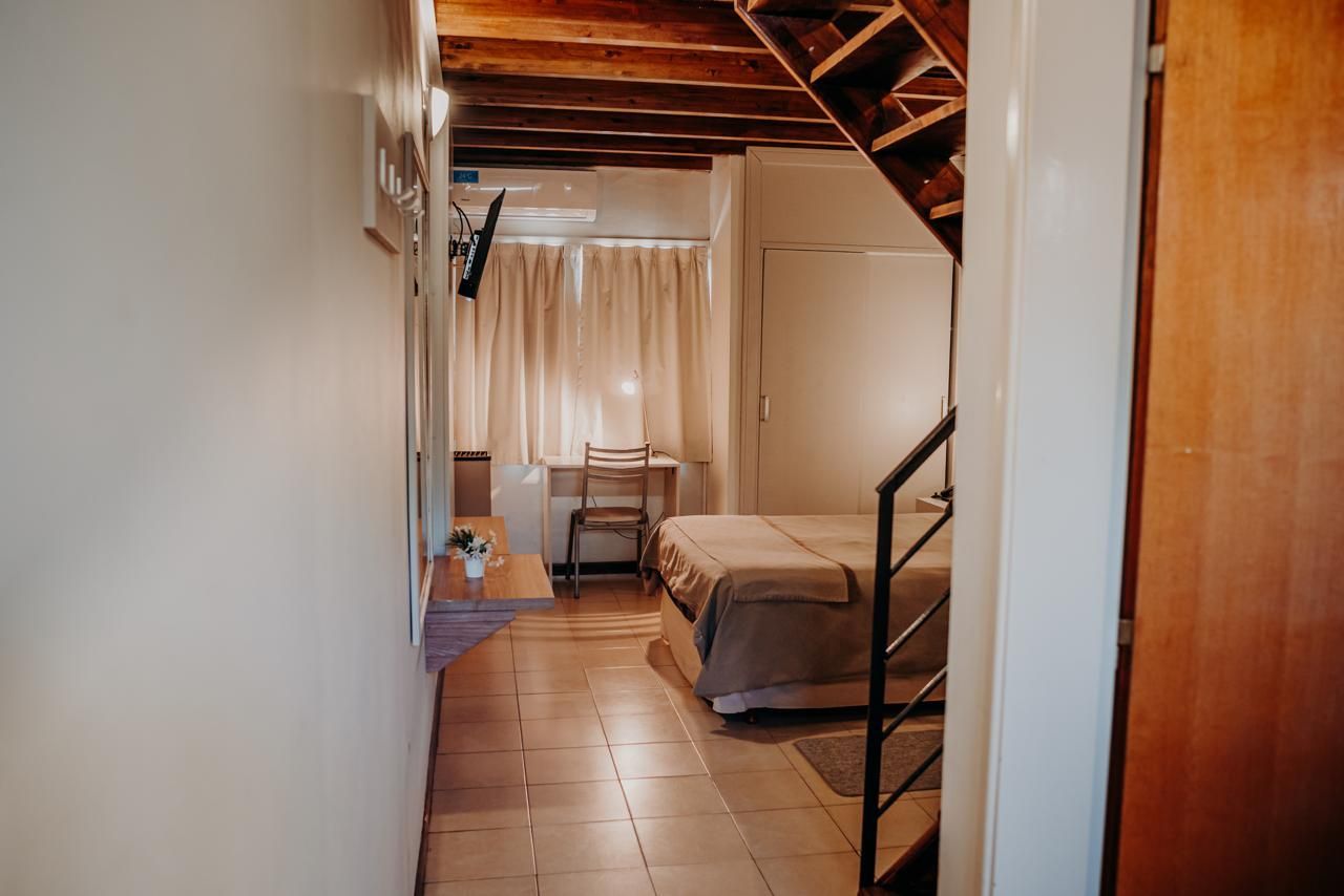 Hallway leading to a bedroom with a bed, desk, window, and wooden ceiling.