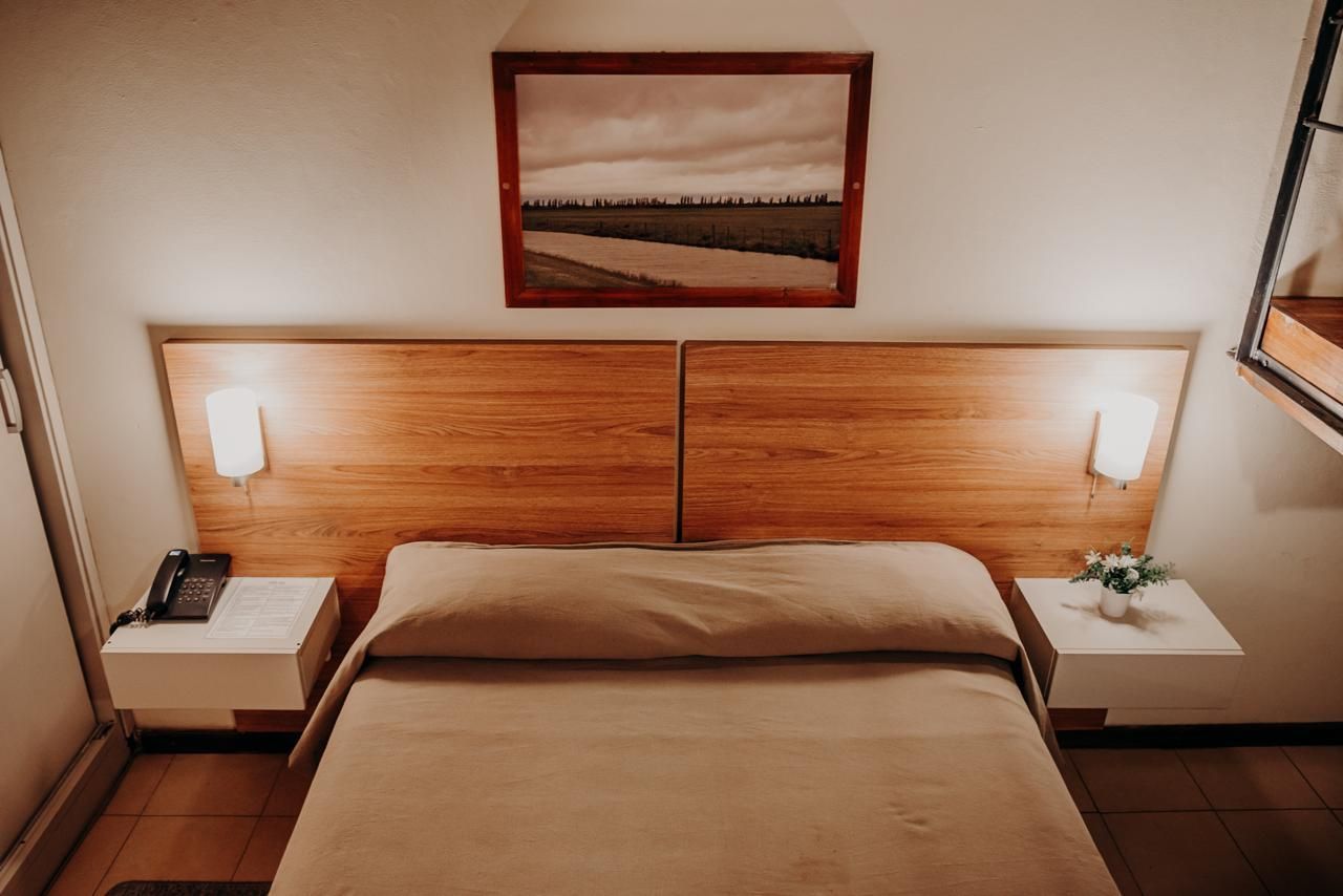 Bedroom with wooden headboard, bed, bedside tables, art, and lamps.