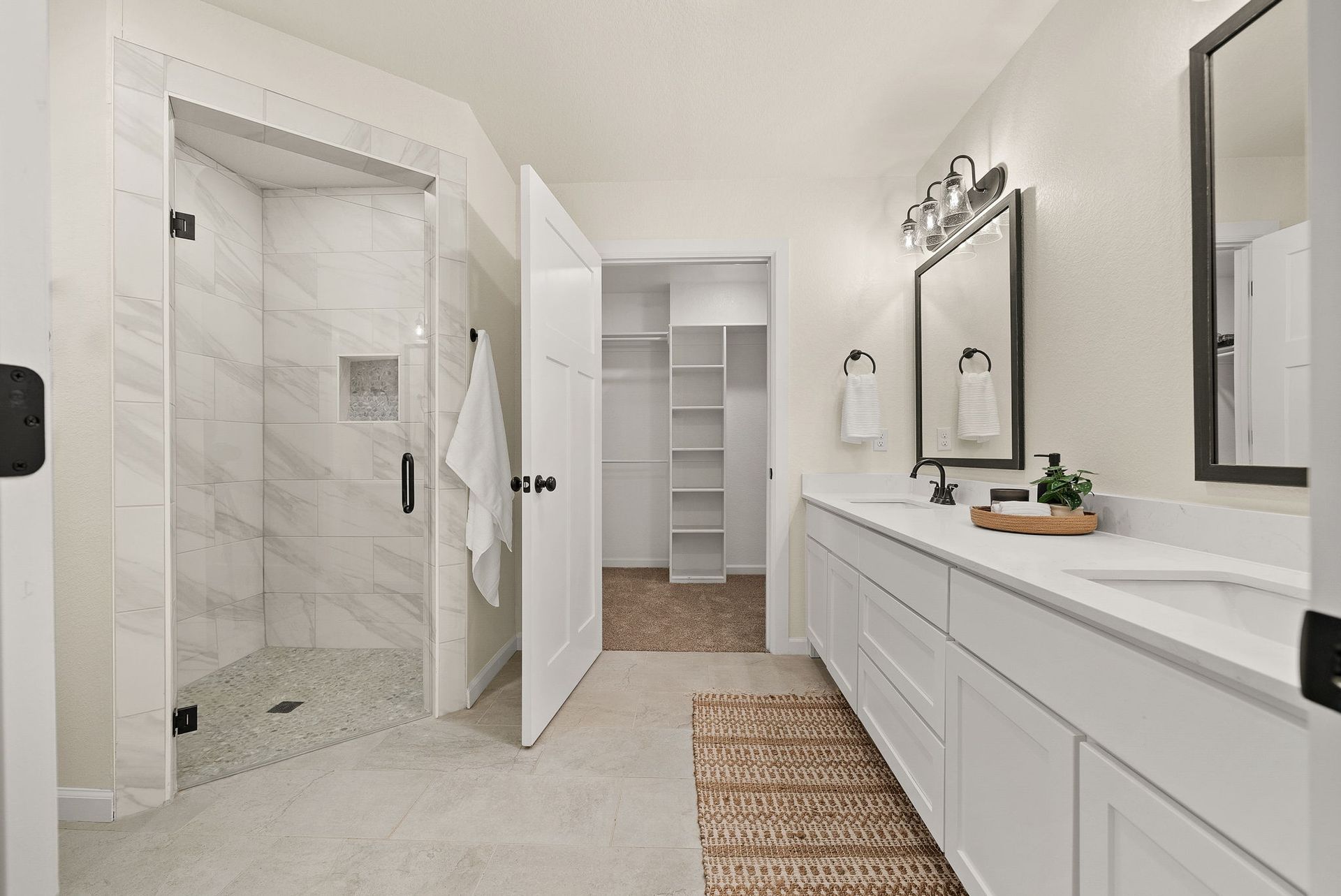 A bathroom with a walk in shower , sink , mirror and closet.