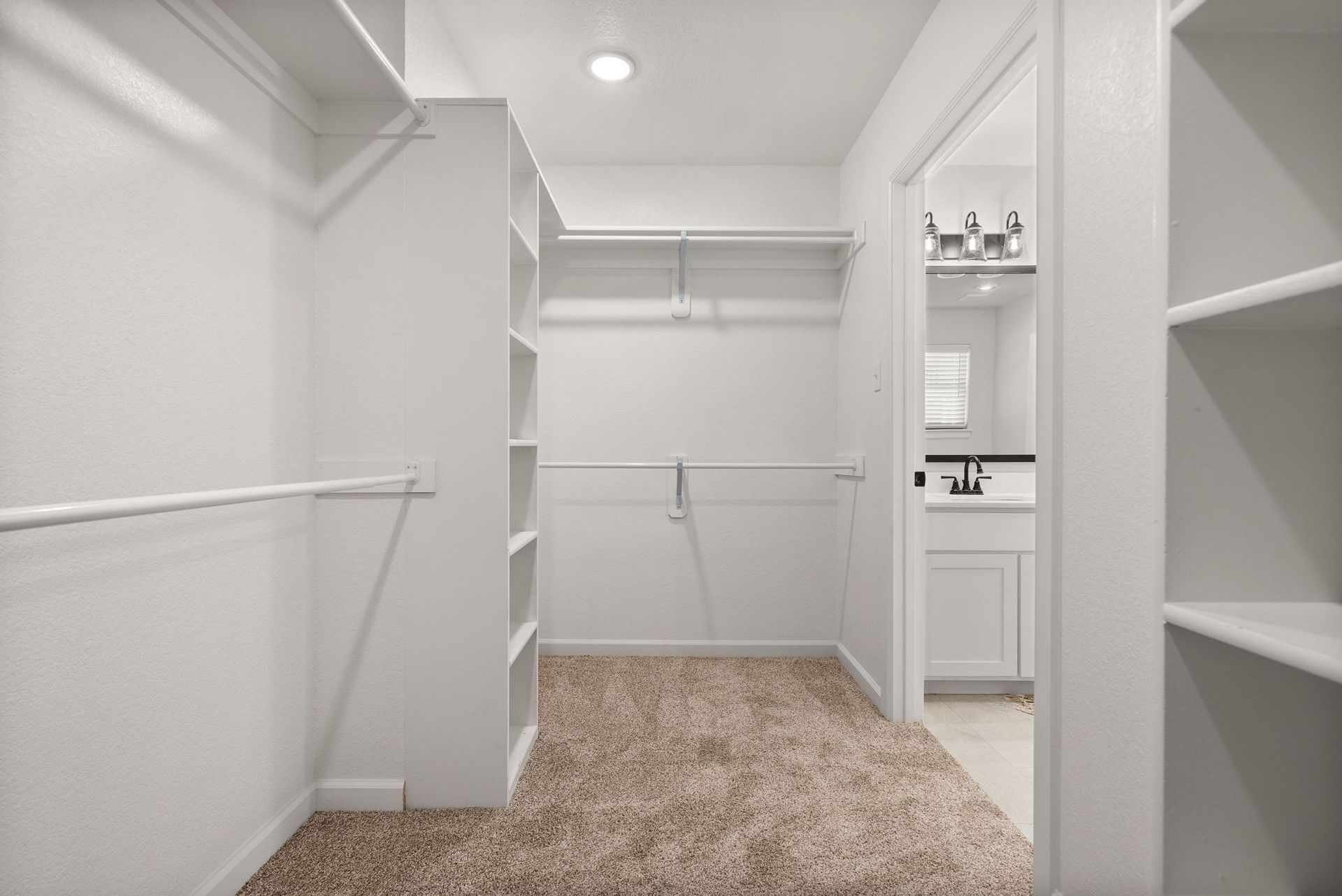 A walk in closet in a house with a bathroom and a sink.