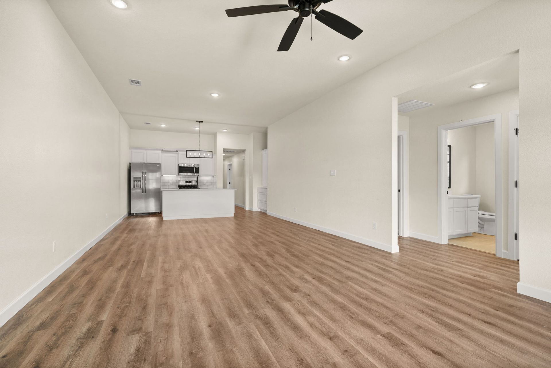 An empty living room with hardwood floors and a ceiling fan.