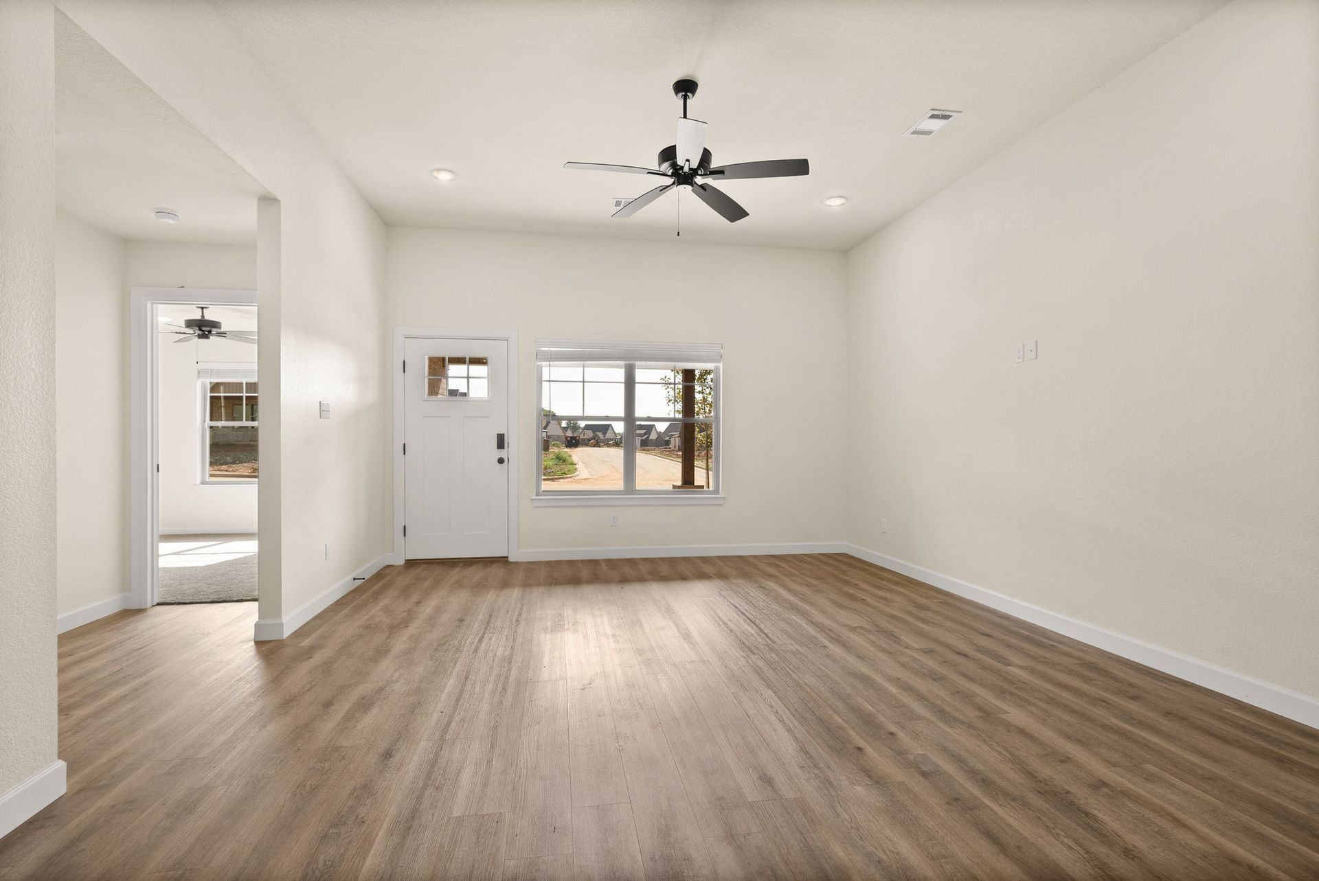 An empty living room with hardwood floors and a ceiling fan.