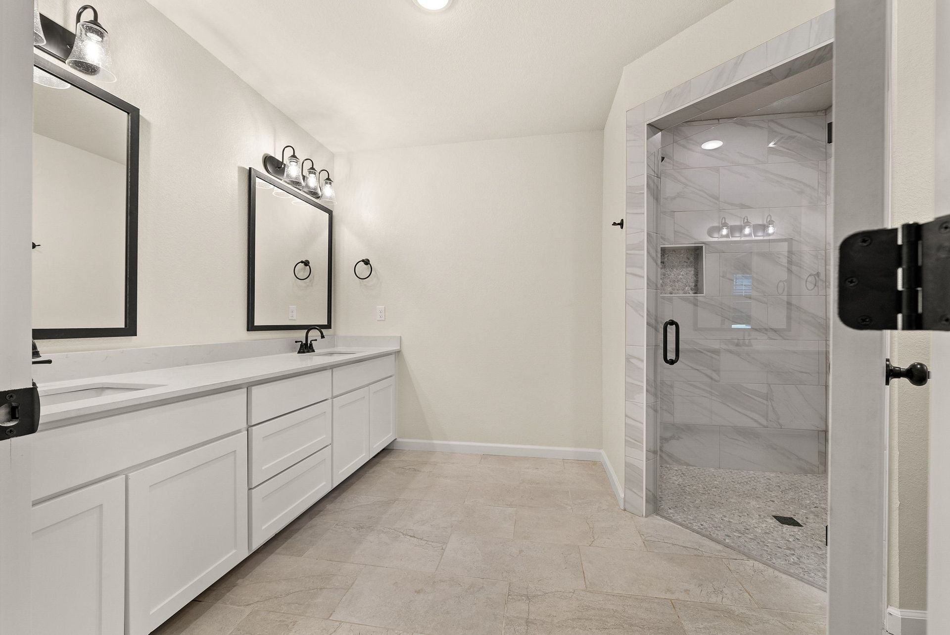 A bathroom with two sinks and a walk in shower.