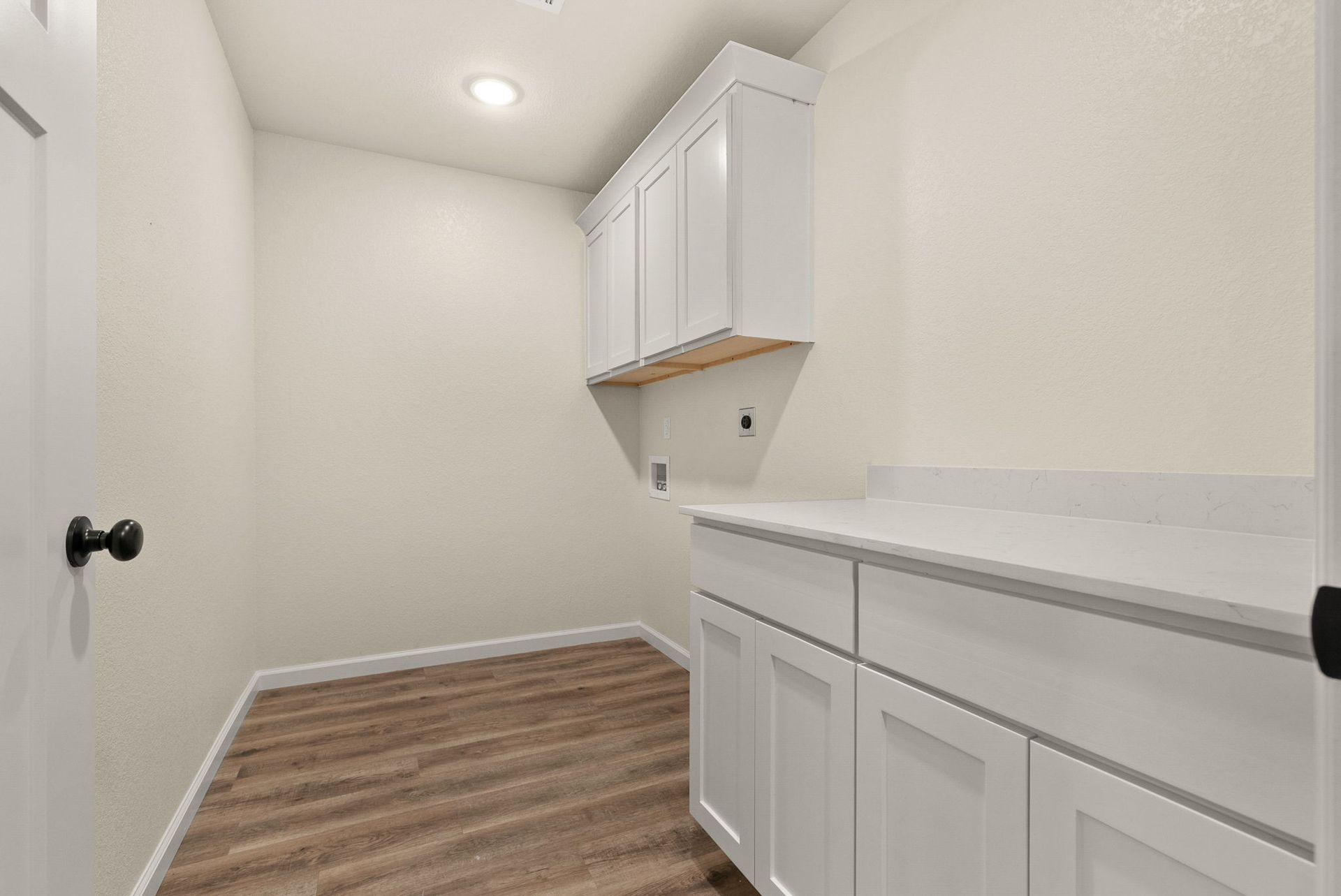 A laundry room with white cabinets and wooden floors.