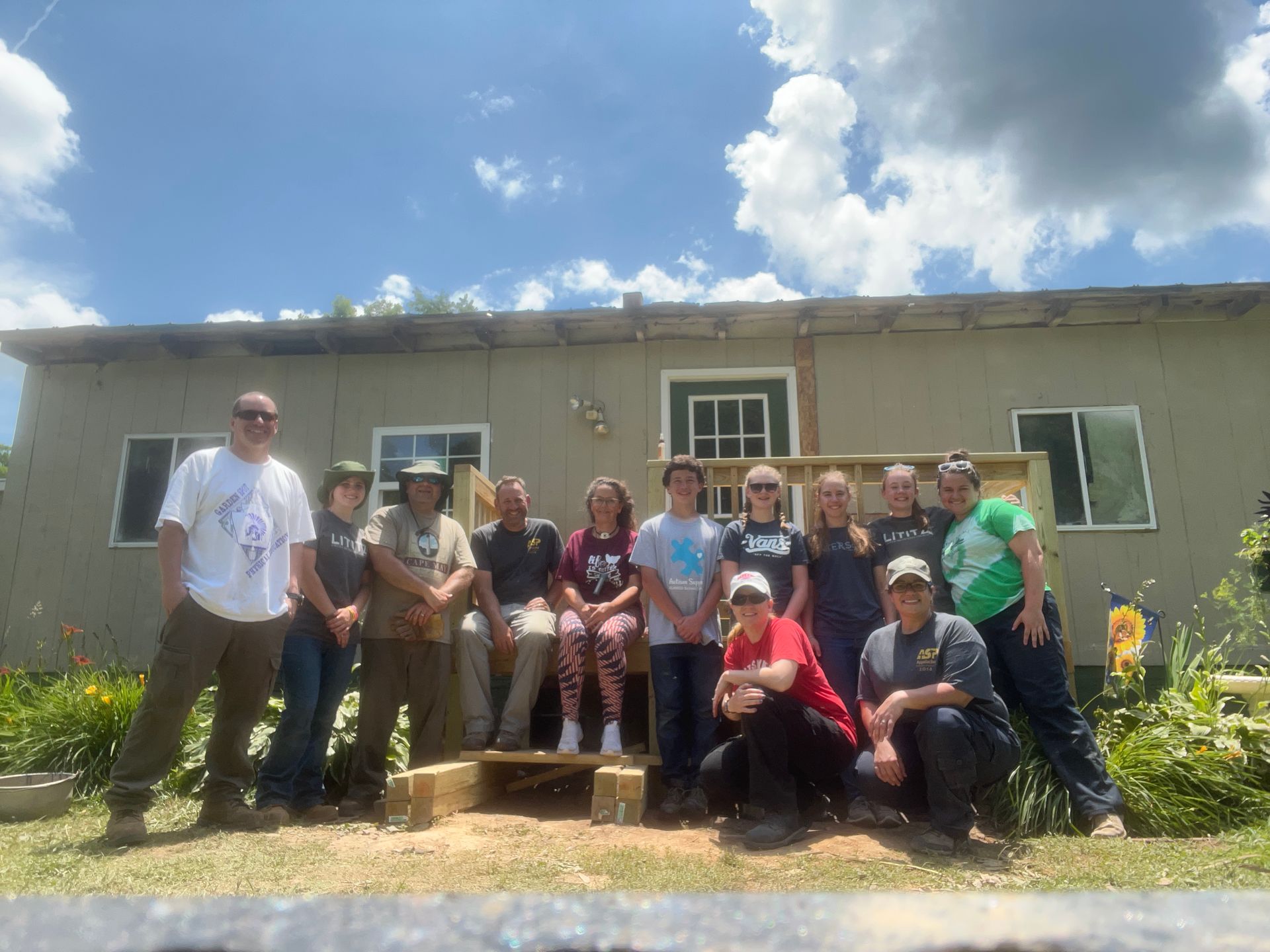A group of people are posing for a picture in front of a house.