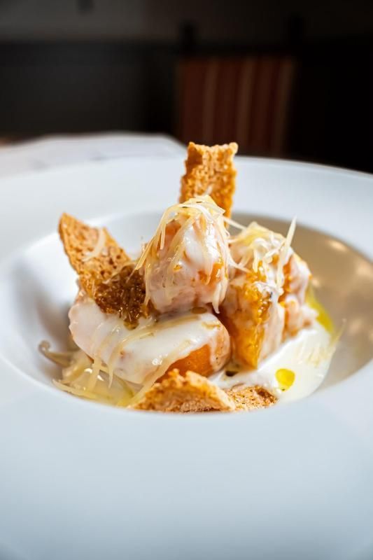 Dessert in una ciotola bianca con cialde croccanti, crema e un filo di salsa