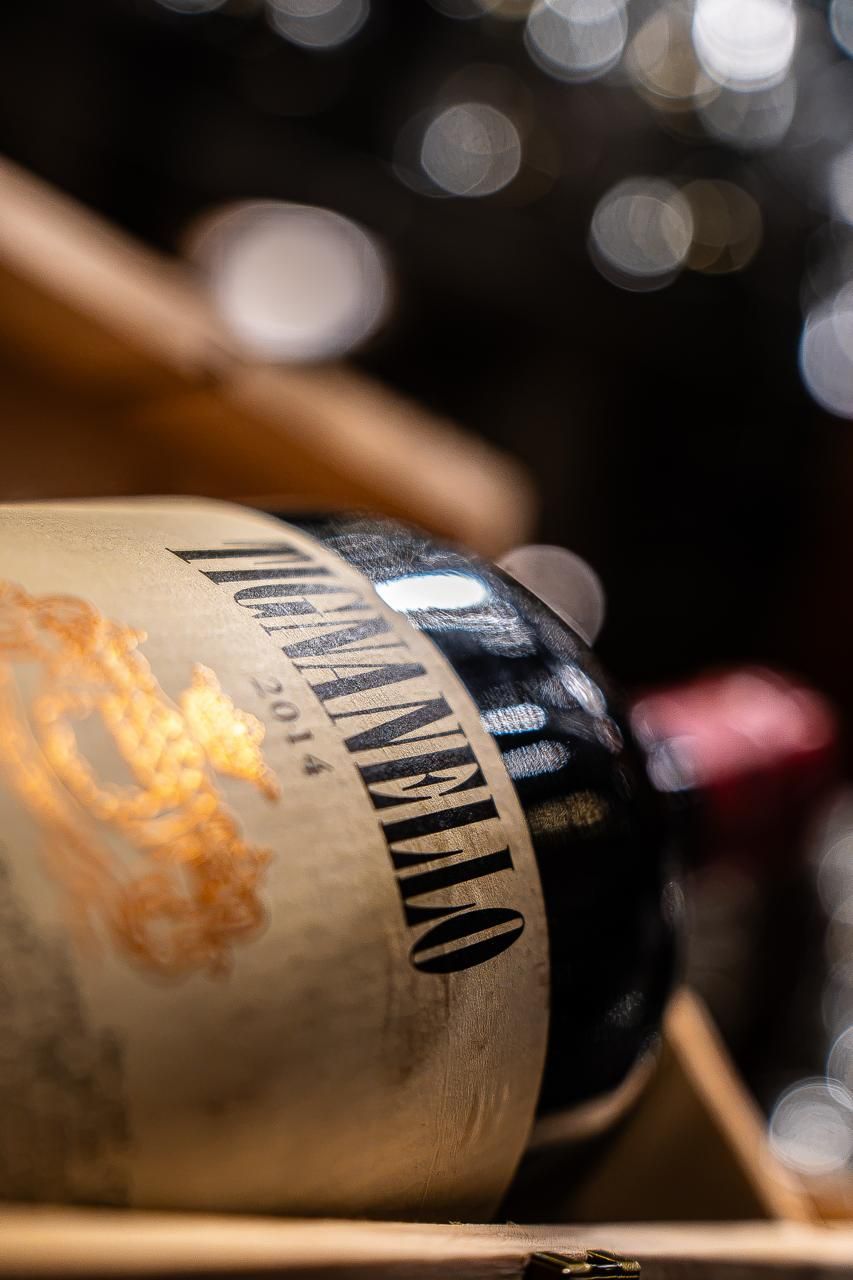 Primo piano dell’etichetta di una bottiglia di vino in una cassa di legno, con bottiglie sfocate sullo sfondo