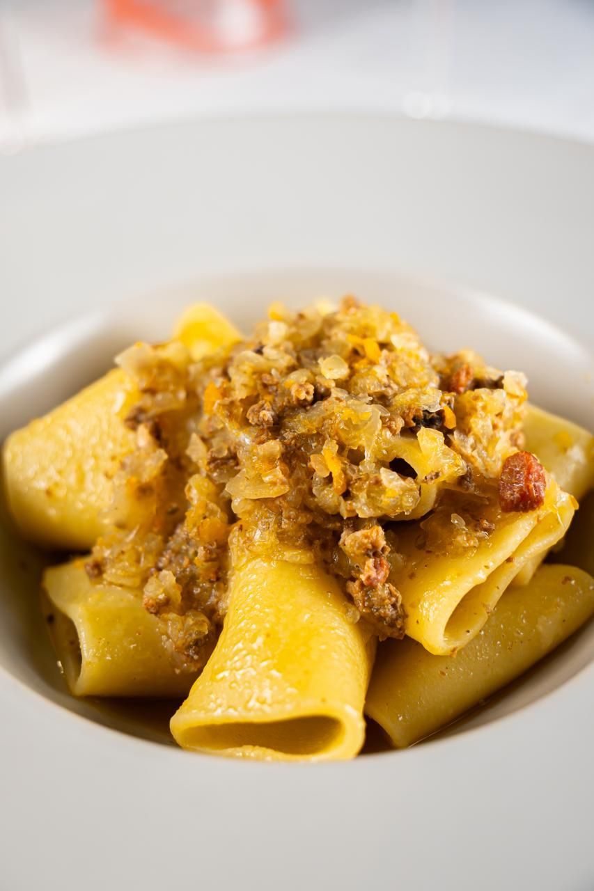 Tubi di pasta conditi con ragù in una ciotola bianca