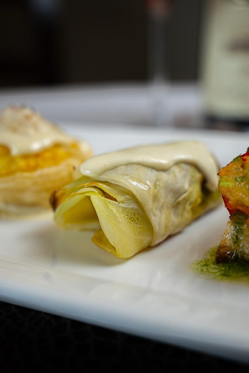 Primo piano di pasta arrotolata impiattata con salsa alla panna e verdure di contorno