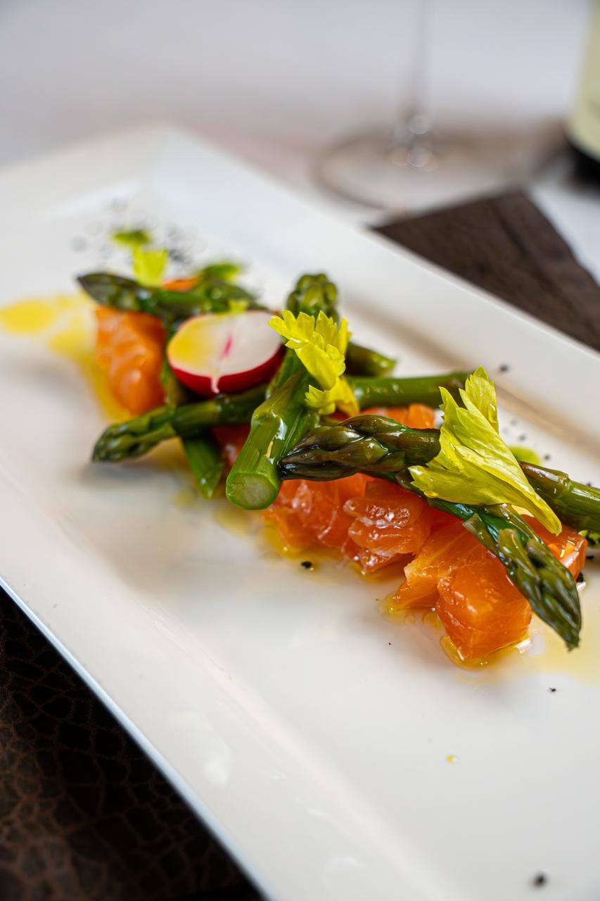 Piatto gourmet di verdure impiattato, con fagiolini, fettine di ravanello e salsa all’arancia, su un piatto bianco