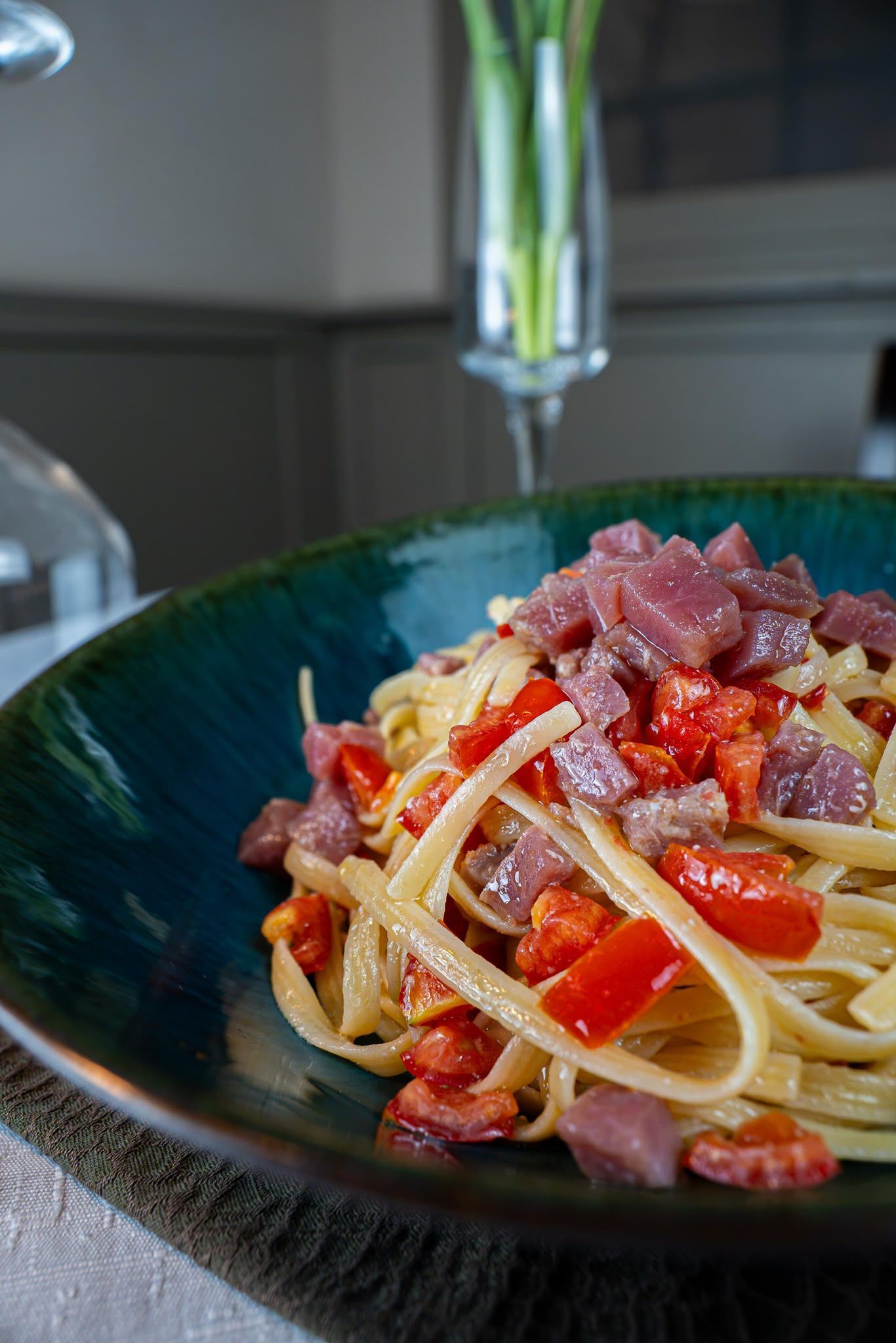 Spaghetti conditi con salsa di pomodoro e carne a dadini in una ciotola scura su un tavolo