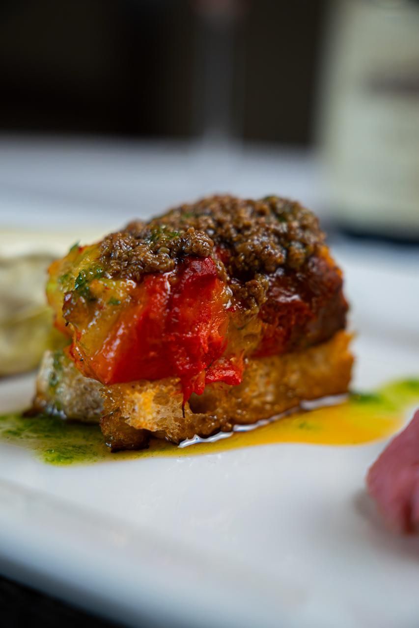 Primo piano di un peperone ripieno con farcitura rossa, condito con salsa e servito su un piatto bianco
