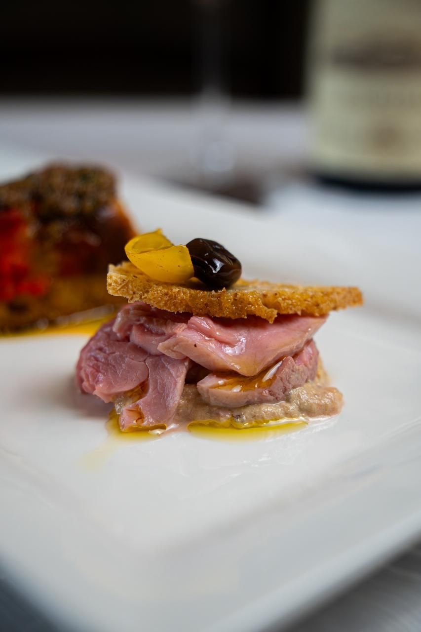 Antipasto gourmet di carne impiattato, guarnito e servito su un piatto bianco