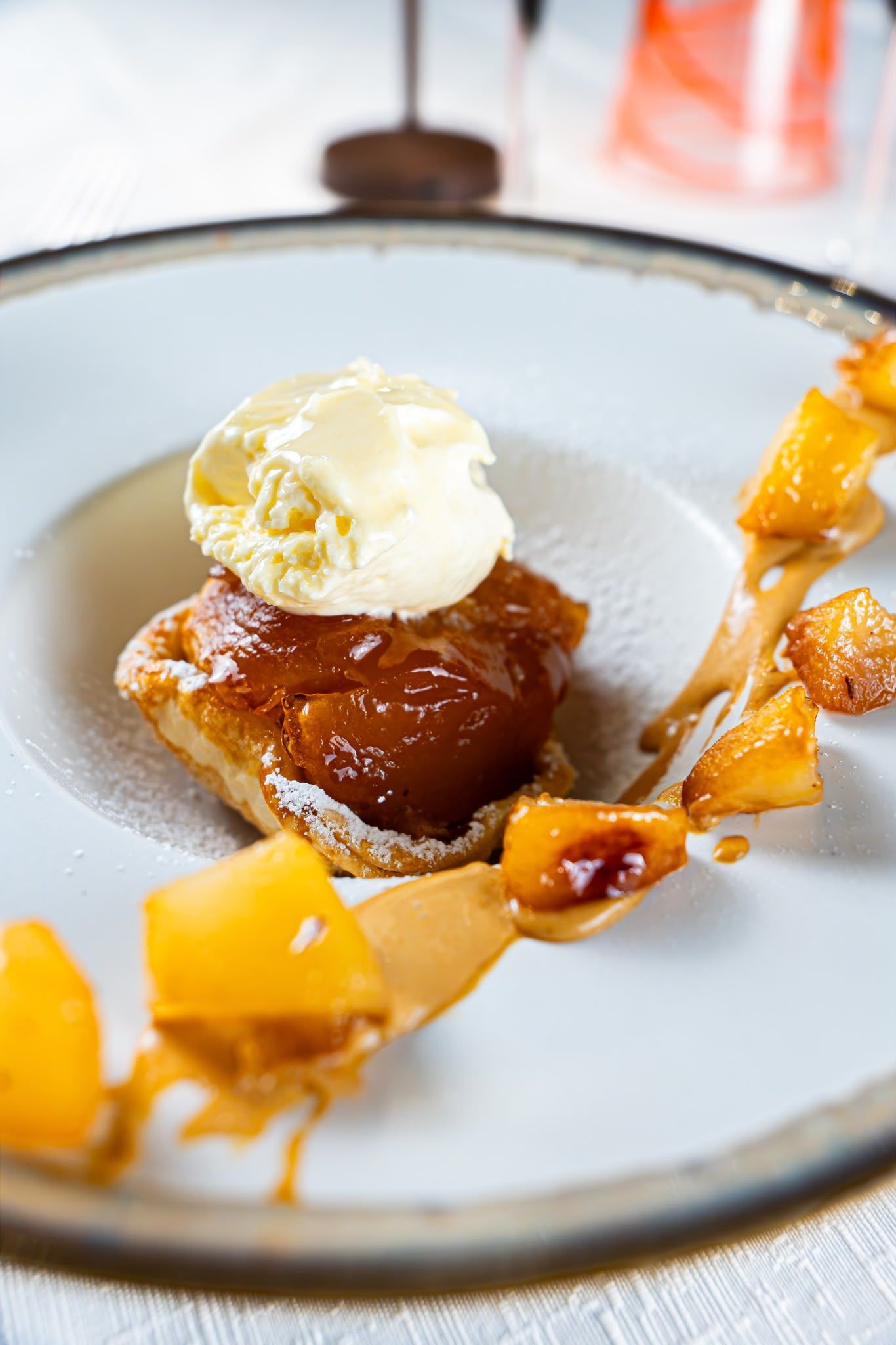 Piatto da dessert con un dolce caramellato, guarnito con gelato alla vaniglia e un filo di salsa all’arancia