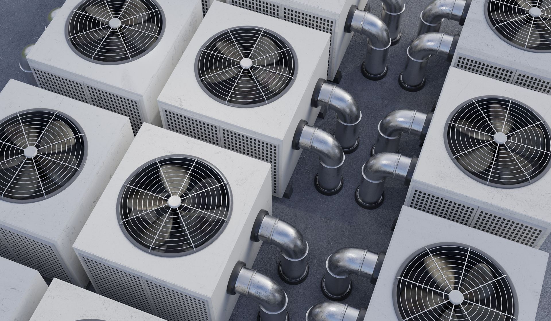 High-angle view of multiple industrial HVAC units with metallic ventilation ducts arranged on a rooftop.