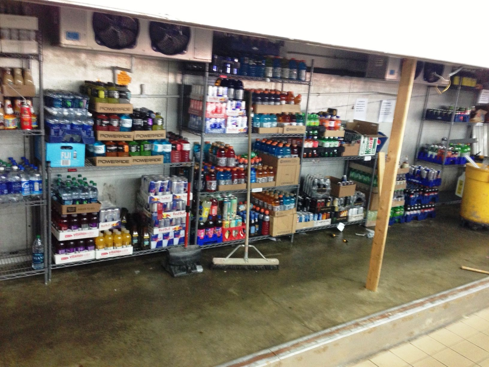Shelves stocked with various bottled beverages and packaged goods inside a storage area or retail backroom.