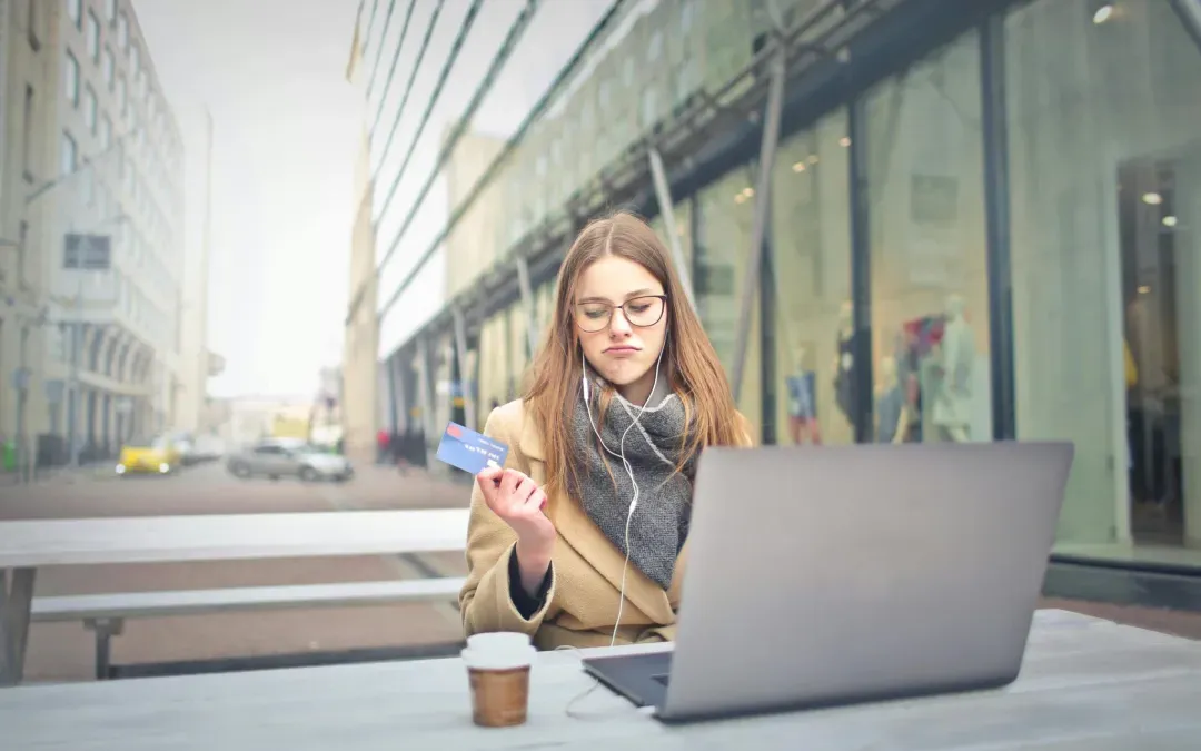 A woman is sitting at a table with a laptop and a credit card.