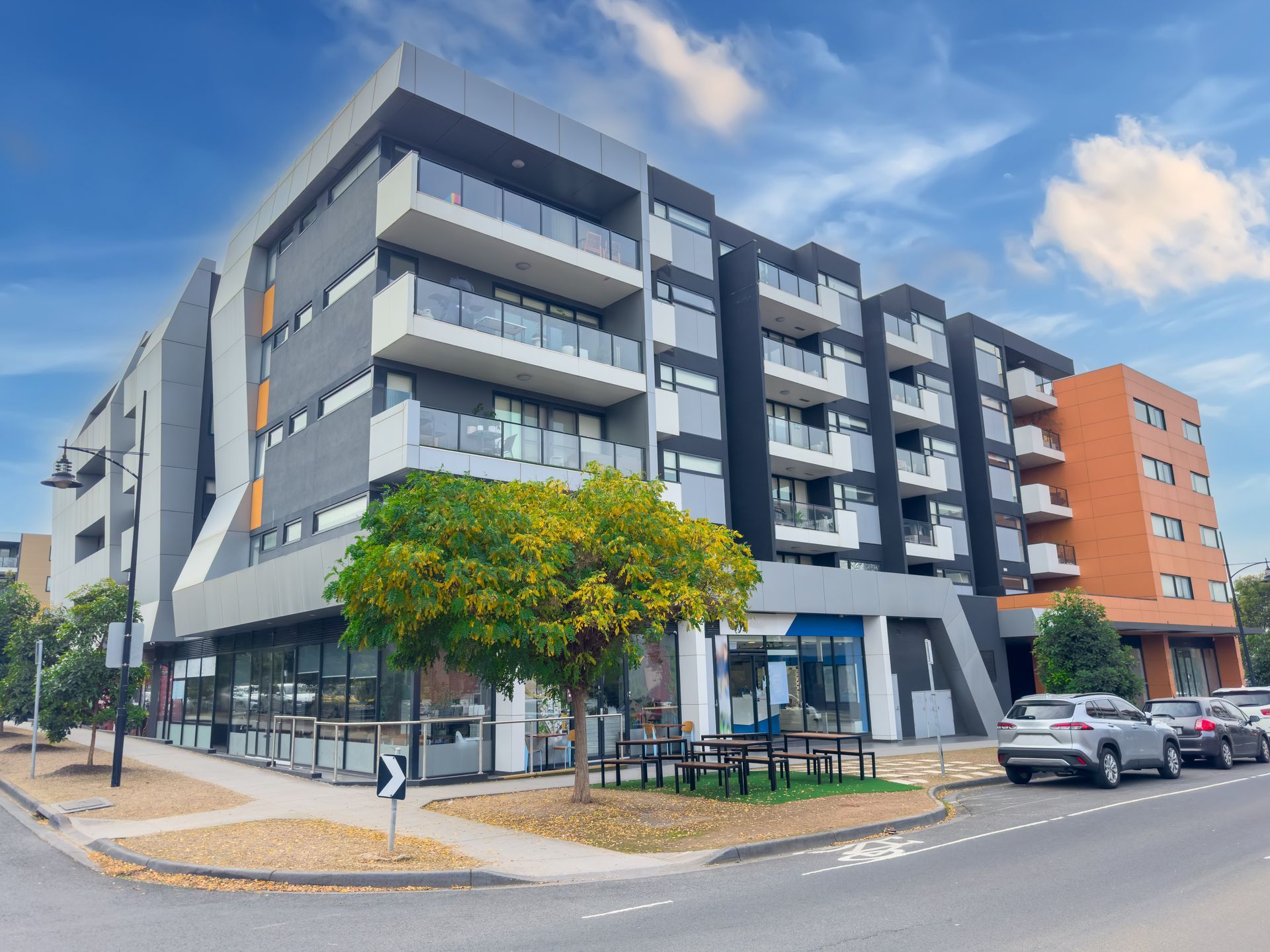 Modern multi-story apartment building with retail on the ground floor.
