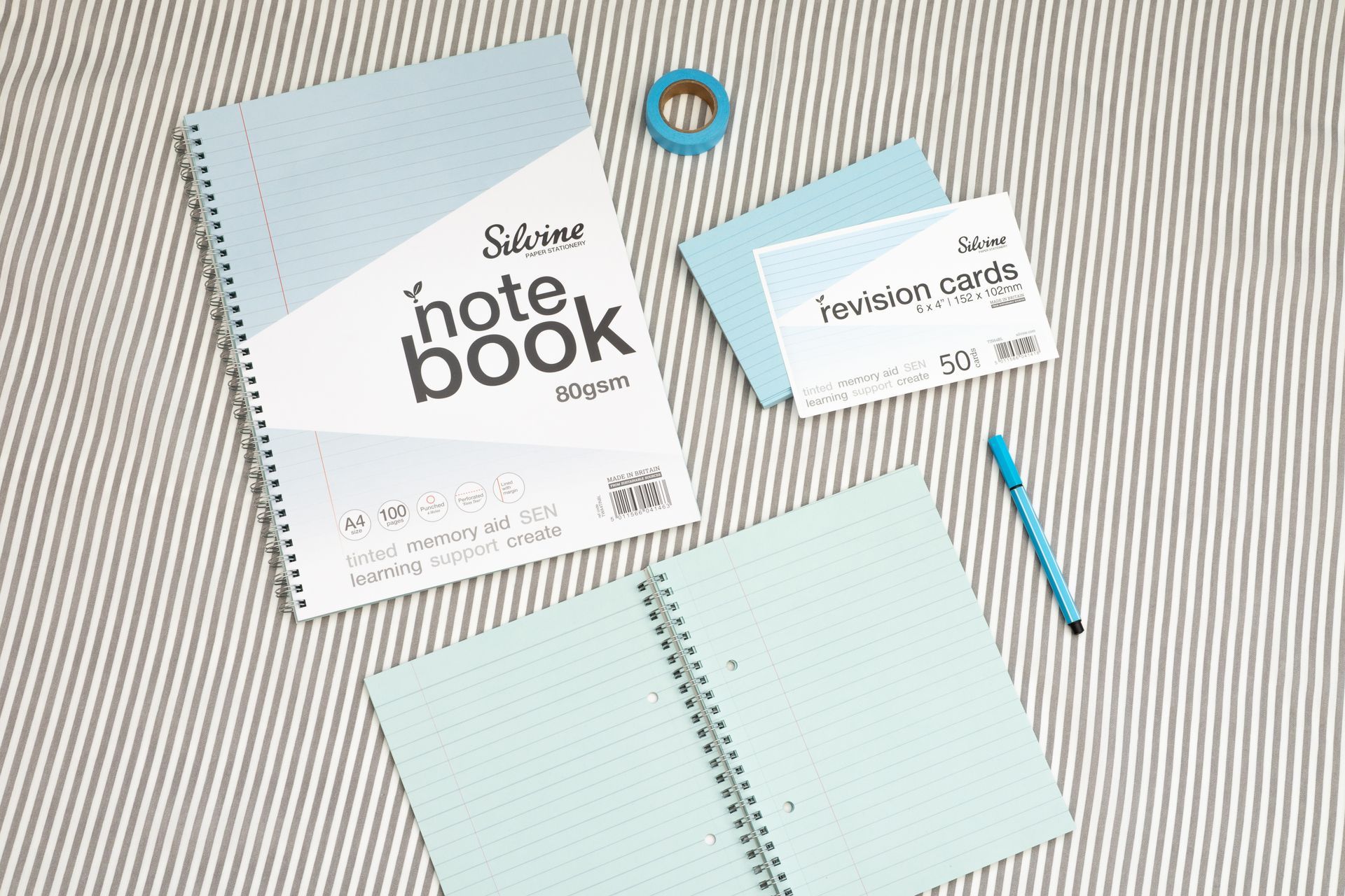 Blue tinted notebook, revision card pack and blue stationery accessories on a grey lined background.