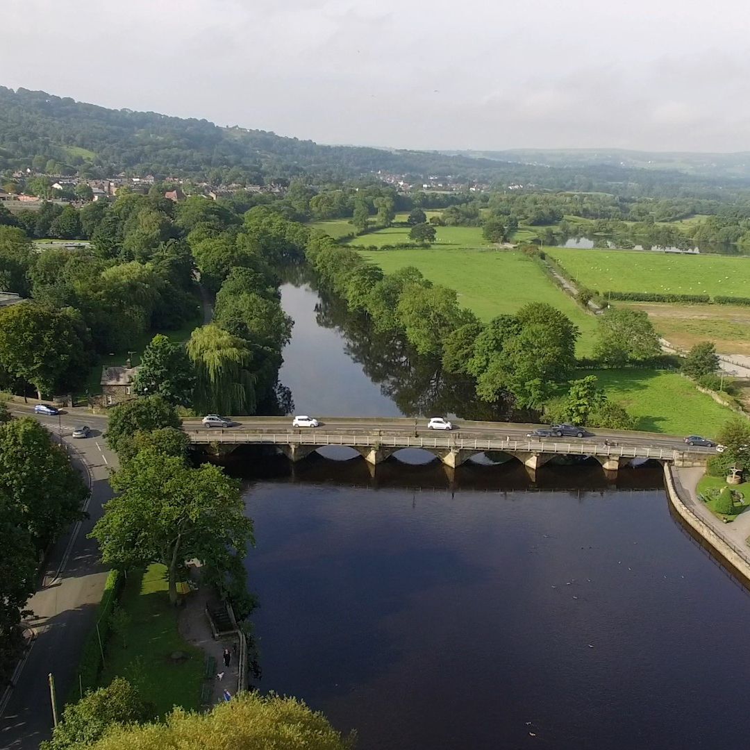 A drone view of cars driving across the bridge in Otley, over the river.