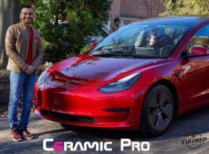 Man standing beside a red Tesla in front of a Ceramic Pro sign