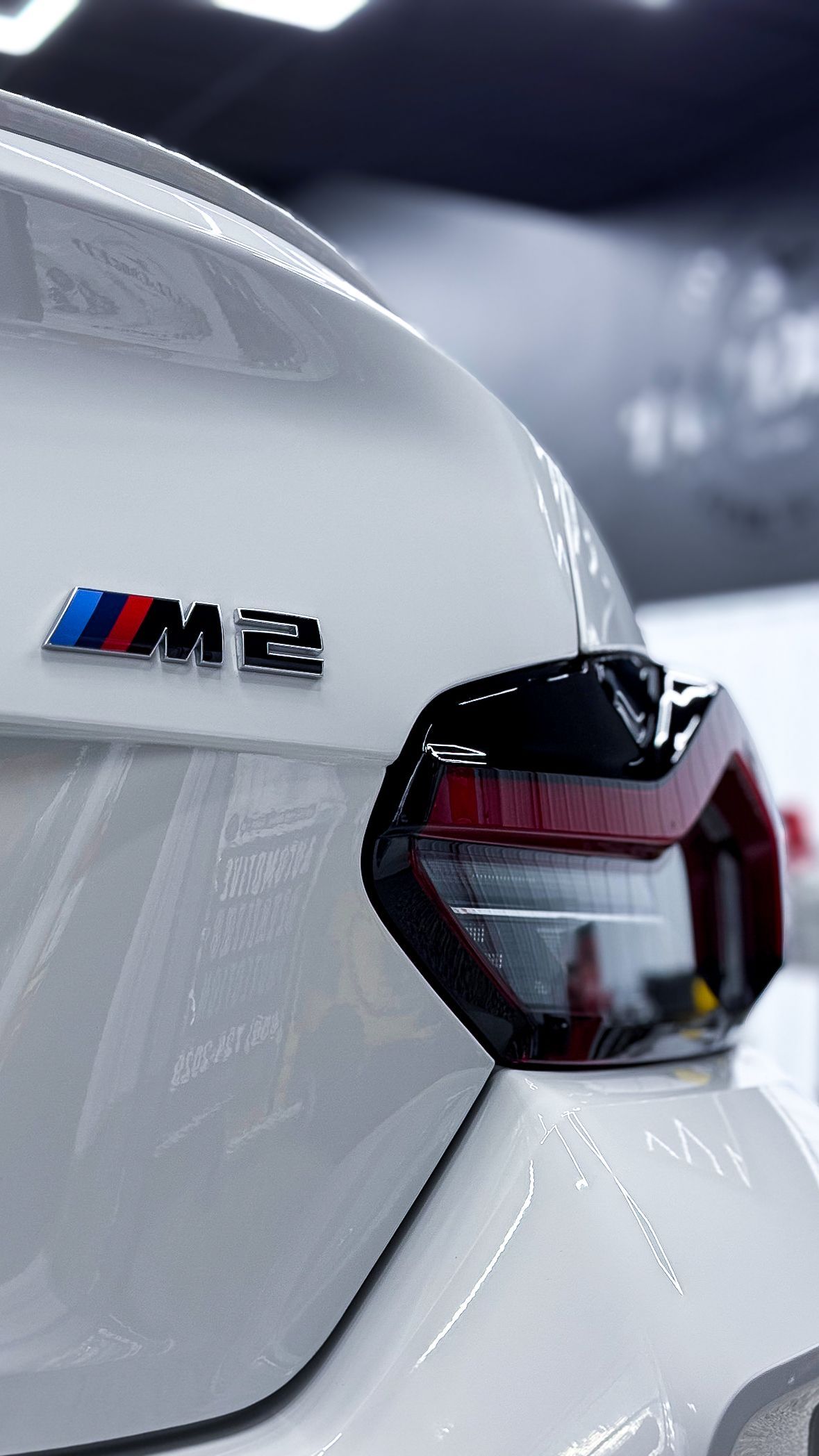 Close-up of a white BMW M badge and taillight in a showroom