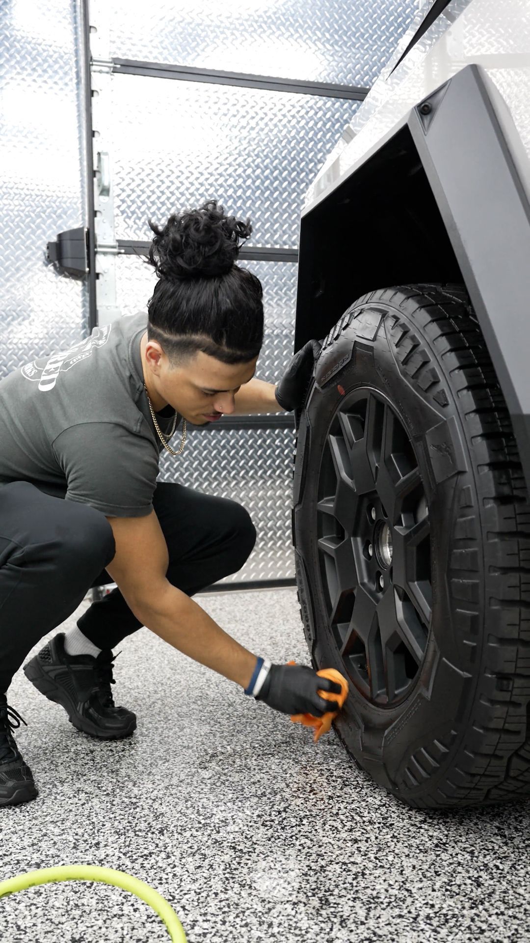 Person tightening a lug nut on a black truck tire with a wrench in a garage