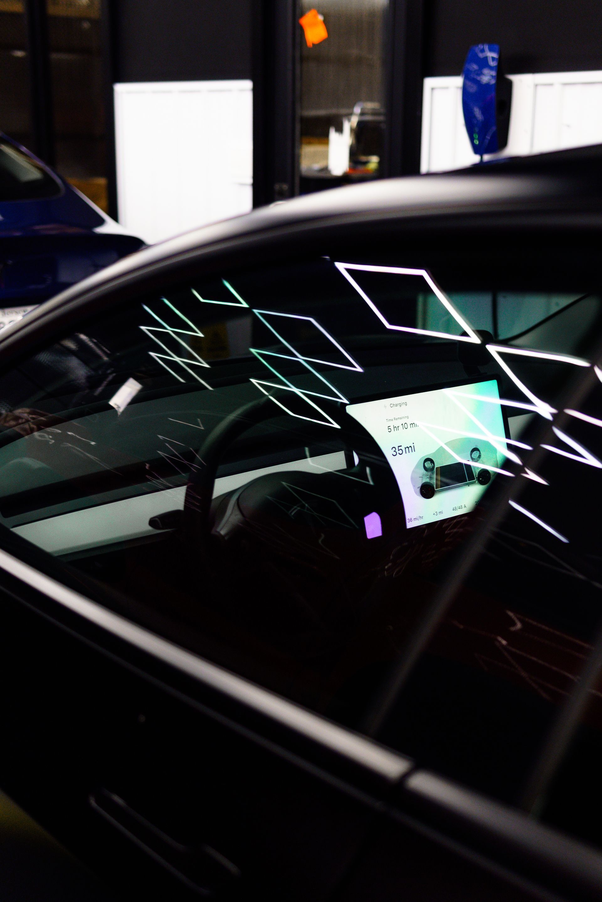 Car at night with neon reflections on the windshield and a lit dashboard inside