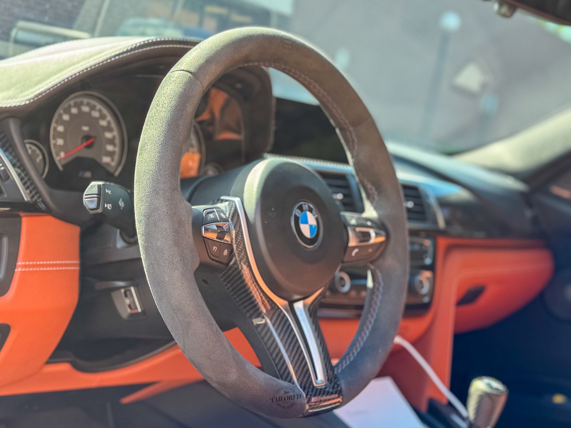 BMW steering wheel with gray suede cover in a red and black car interior
