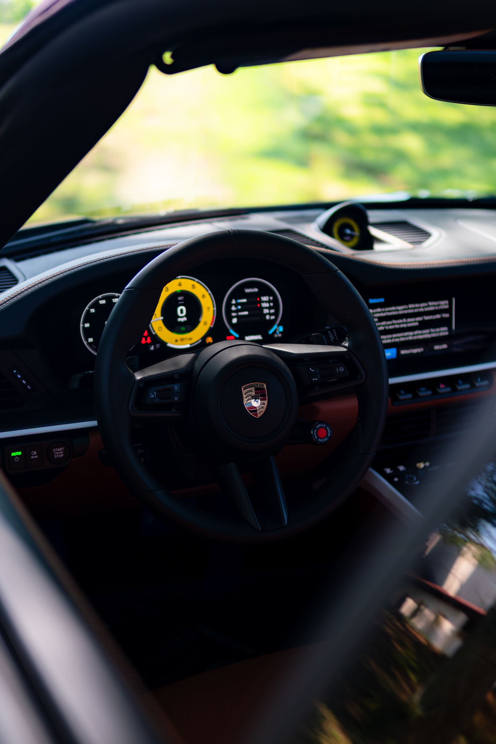 Car interior with steering wheel and digital dashboard, seen through the open driver’s side window