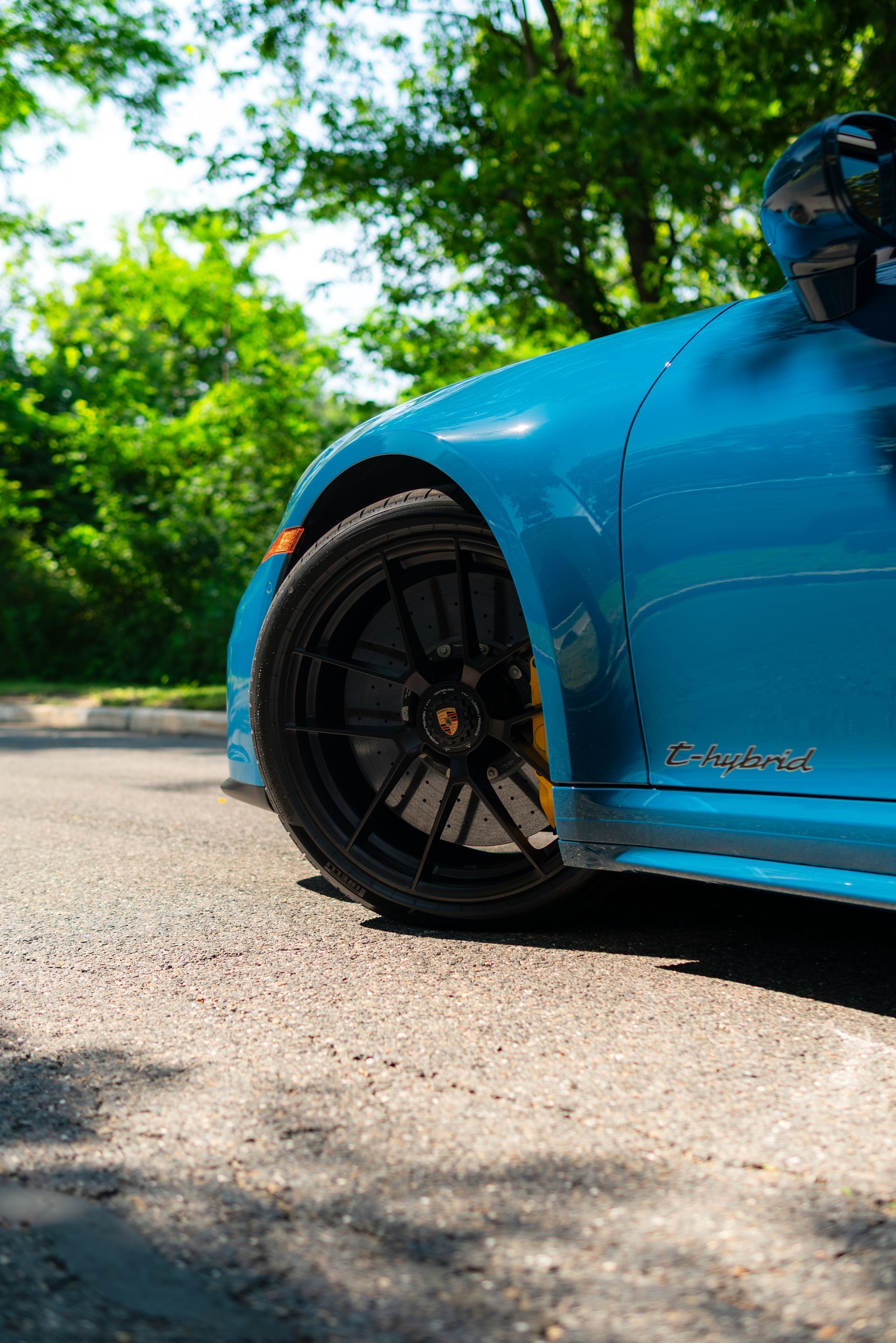 Blue sports car close-up on a sunny road, showing the front wheel and fender.