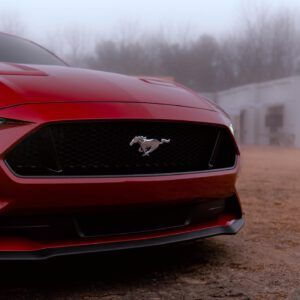 Red Ford Mustang front end in a foggy outdoor setting