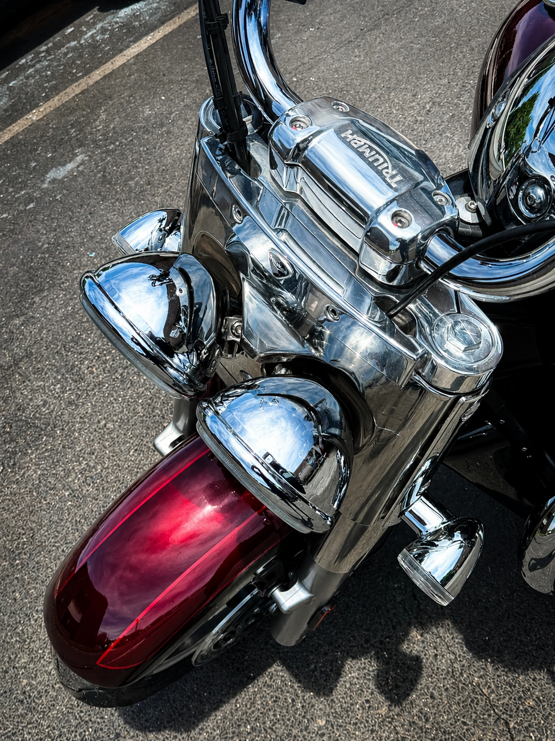 Chrome motorcycle with a red rear tail light, viewed from above on pavement