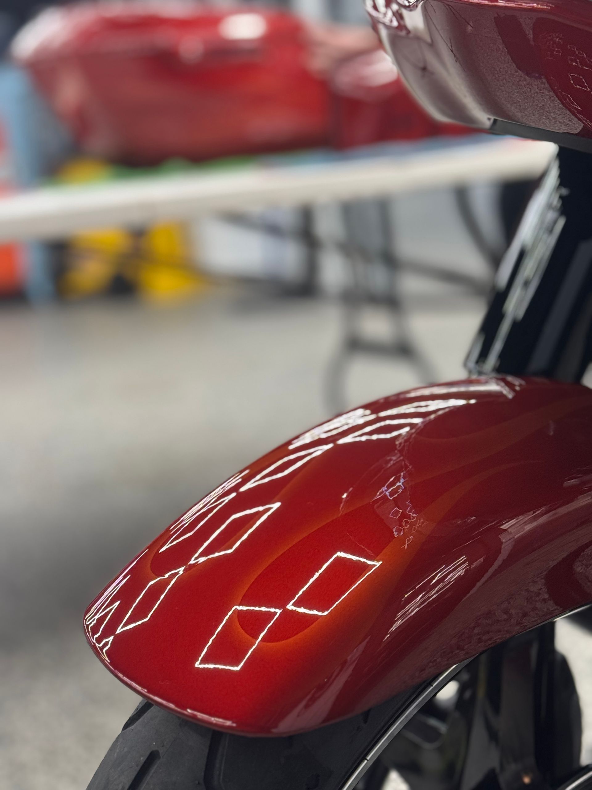 Glossy red car hood with bright light reflections in a showroom