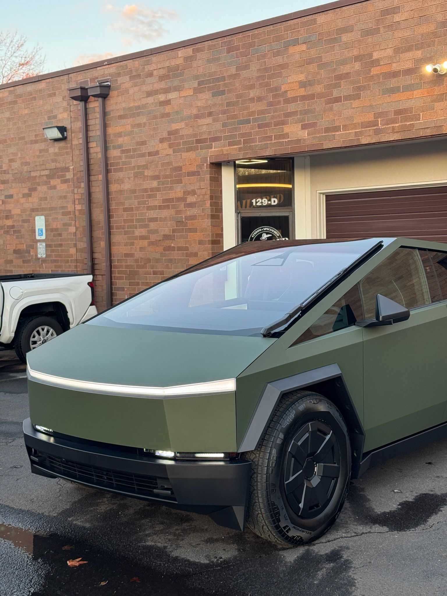 Tesla Cybertruck parked outside a brick building, shown front-left in daylight.