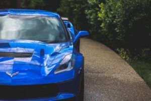 Blue sports car on a winding road beside dense green trees