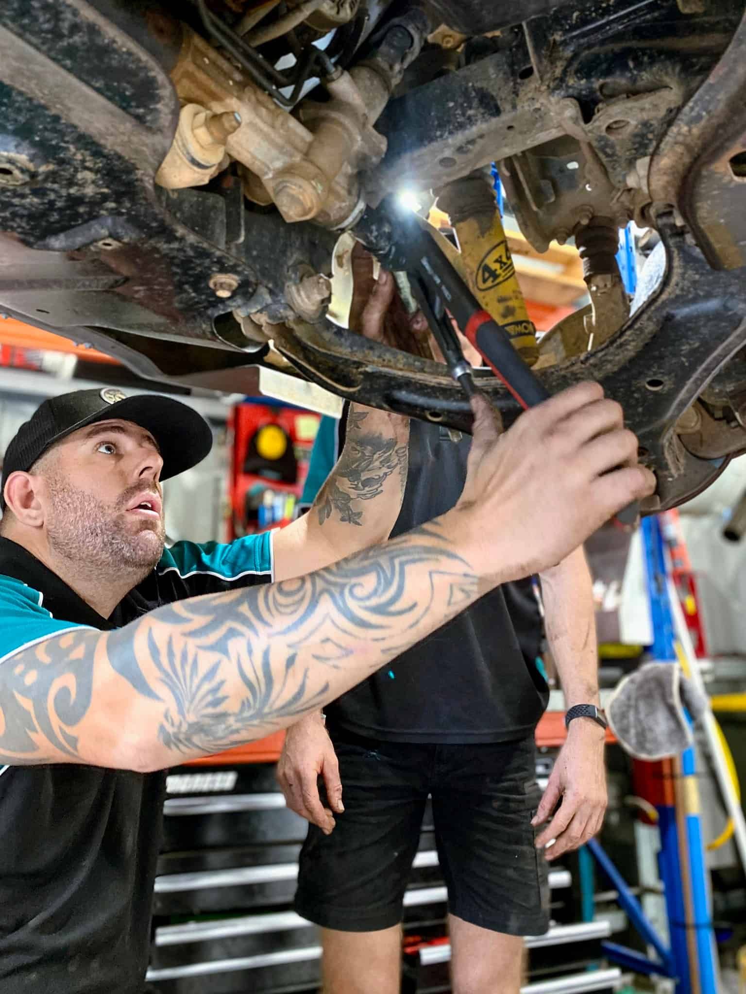 A Man is Working on the Underside of a Car in a Garage — OSP Automotive & Marine In Grafton, NSW