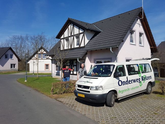 Een witte bestelbus staat overdag geparkeerd voor een huis in een woonwijk.