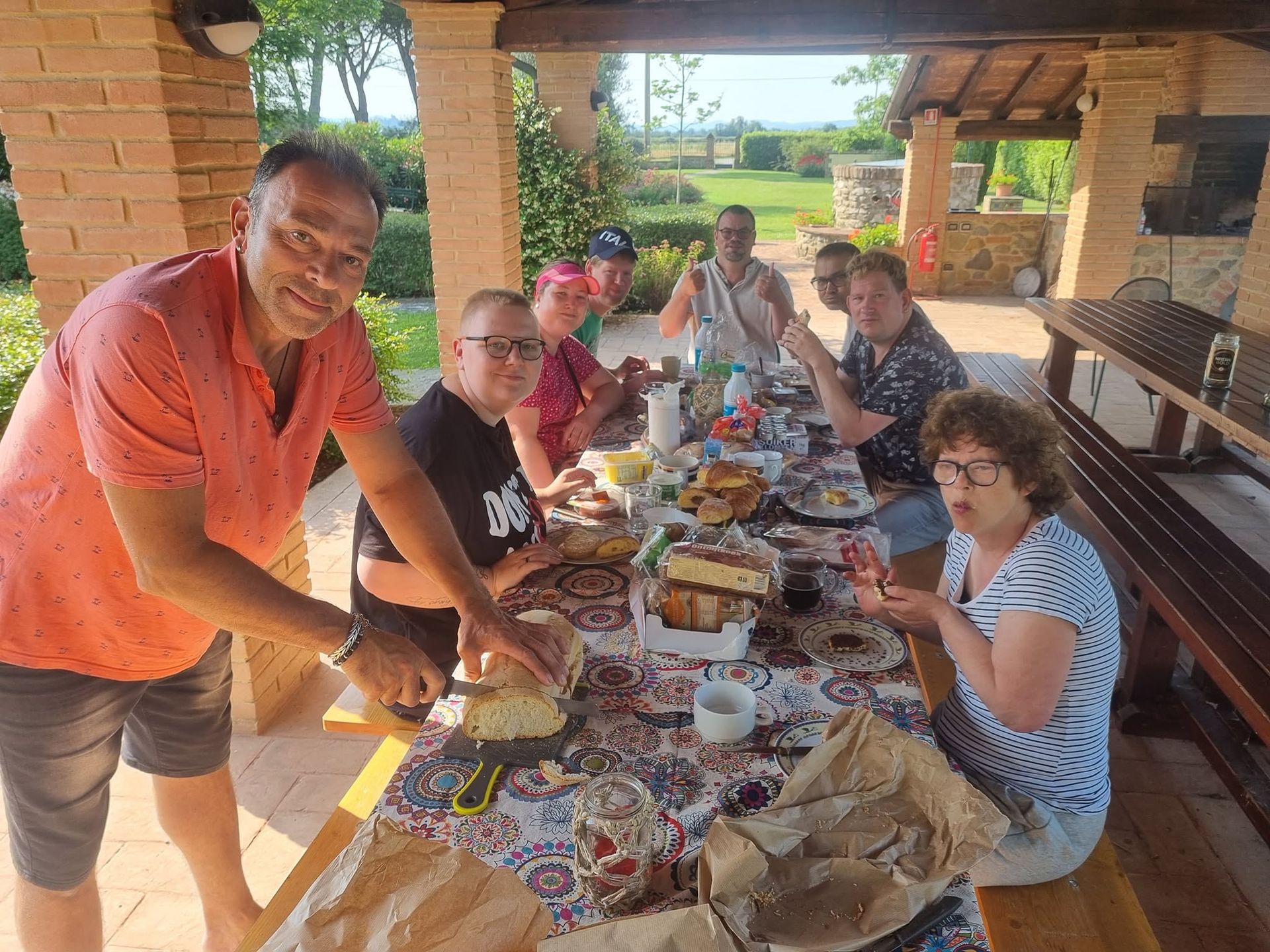 Vrienden zaten rond een picknicktafel en deelden hun eten onder een schaduwrijk afdakje.