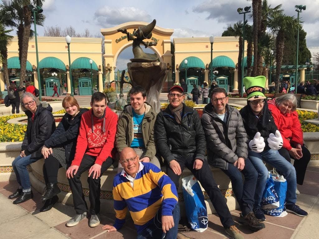 Een groep mensen zit op een bankje voor een fontein in een park of op een plein.