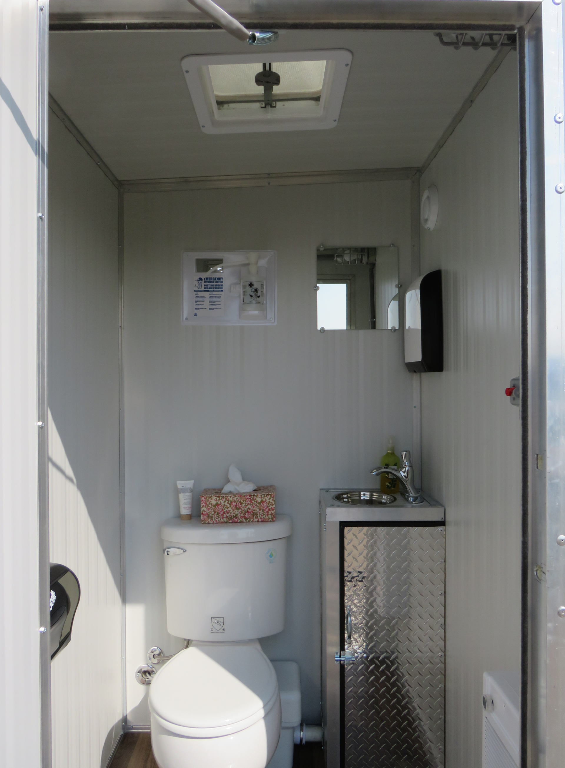 Single-unit washroom trailers interior with a toilet, small sink and ventilation skylight.