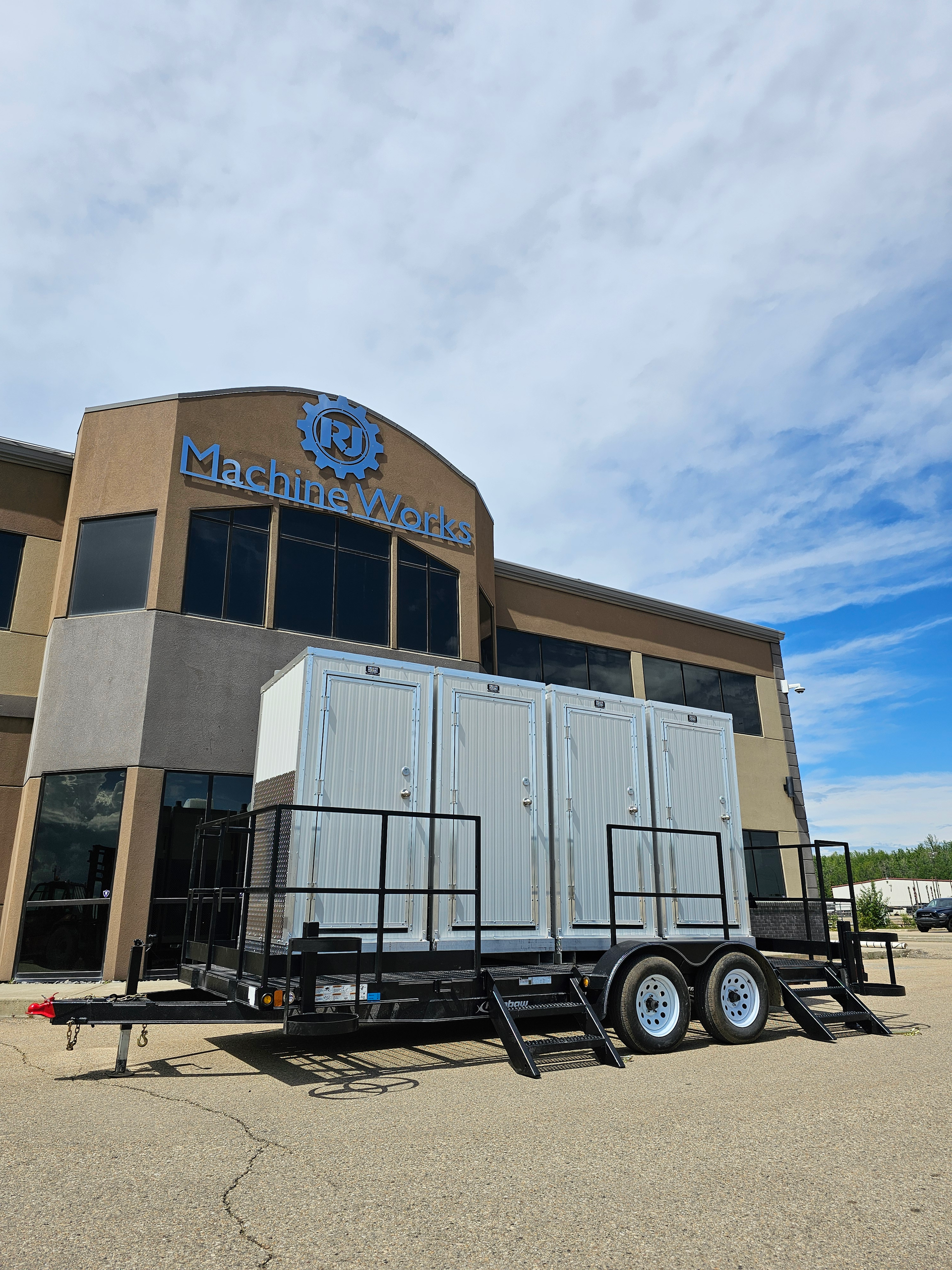 Modern portable offices built on a trailer, parked outside a corporate building, featuring multiple doors and elevated stairs for easy access.