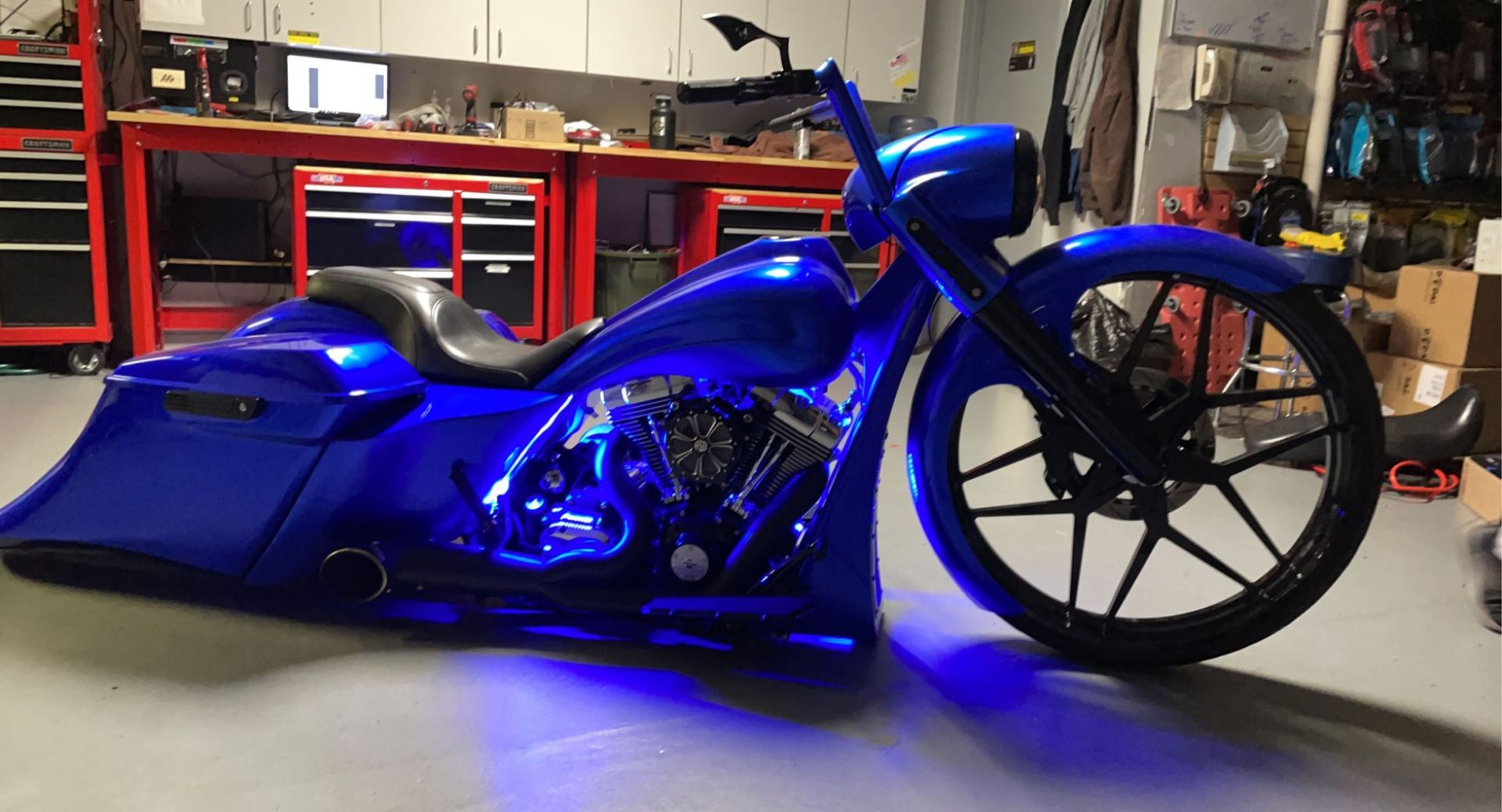 Blue custom motorcycle in a garage, lit by blue underglow lights.