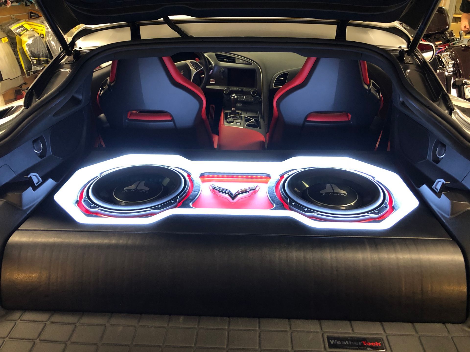 Open car trunk with custom illuminated subwoofer audio installation and two racing-style seats behind it