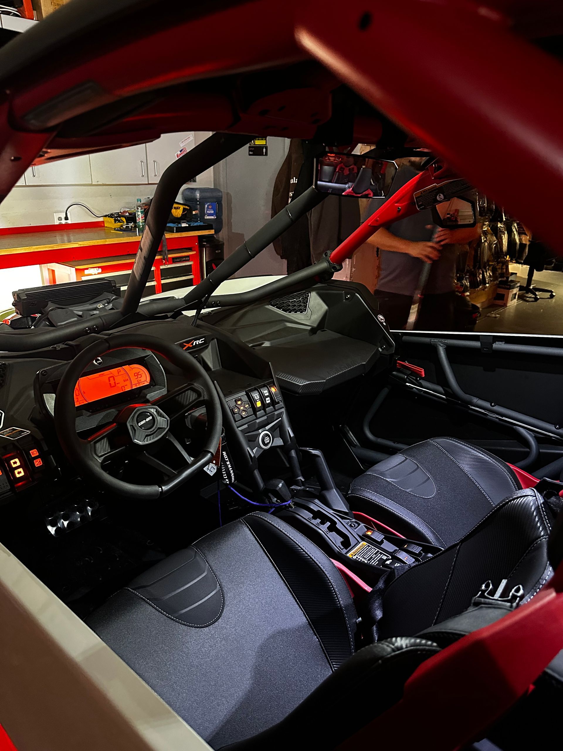 Red off-road vehicle interior with racing seats, steering wheel, and roll cage in a garage