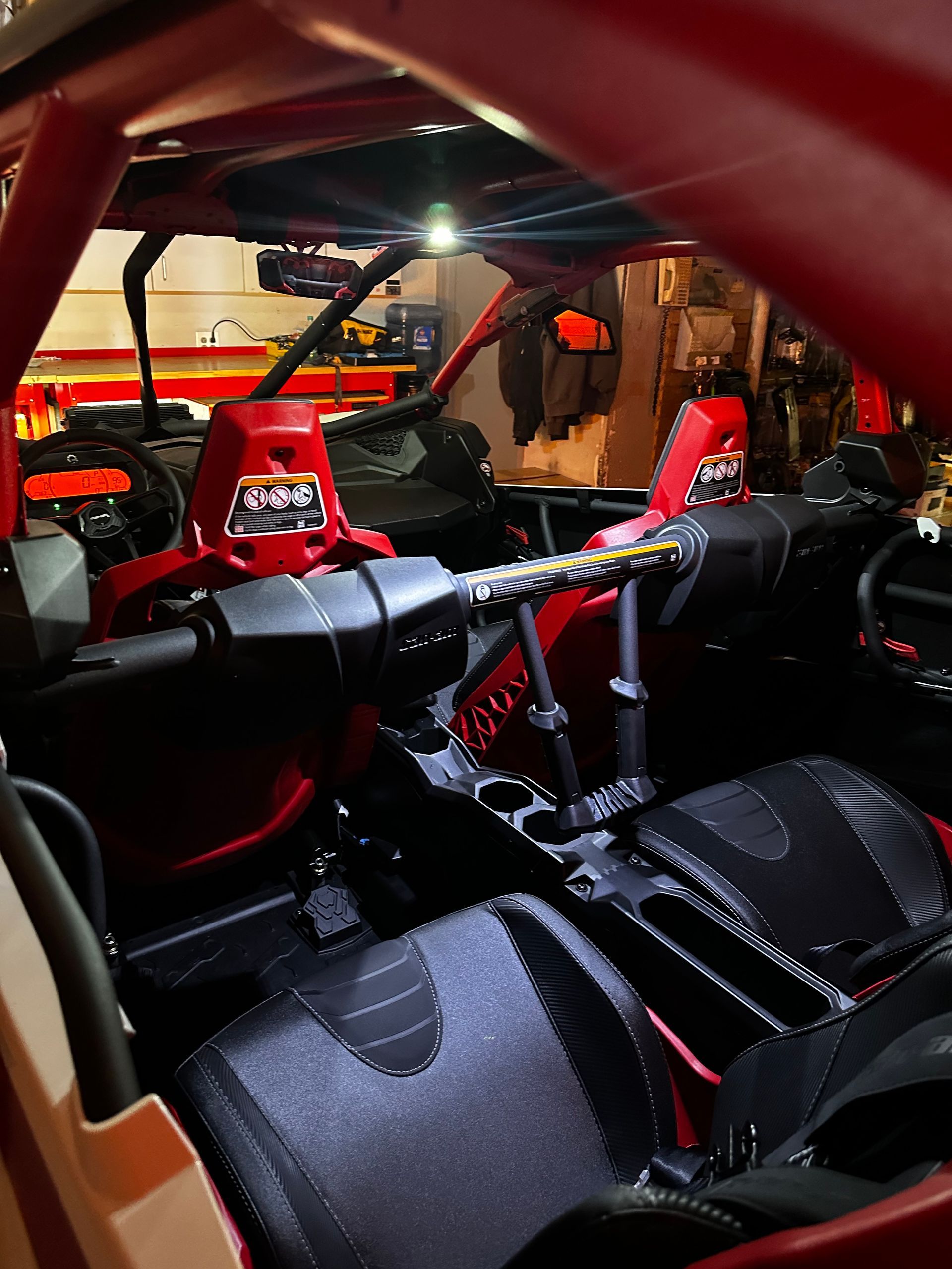 Red race car interior with roll cage, steering wheel, and bucket seats at a motorsport event