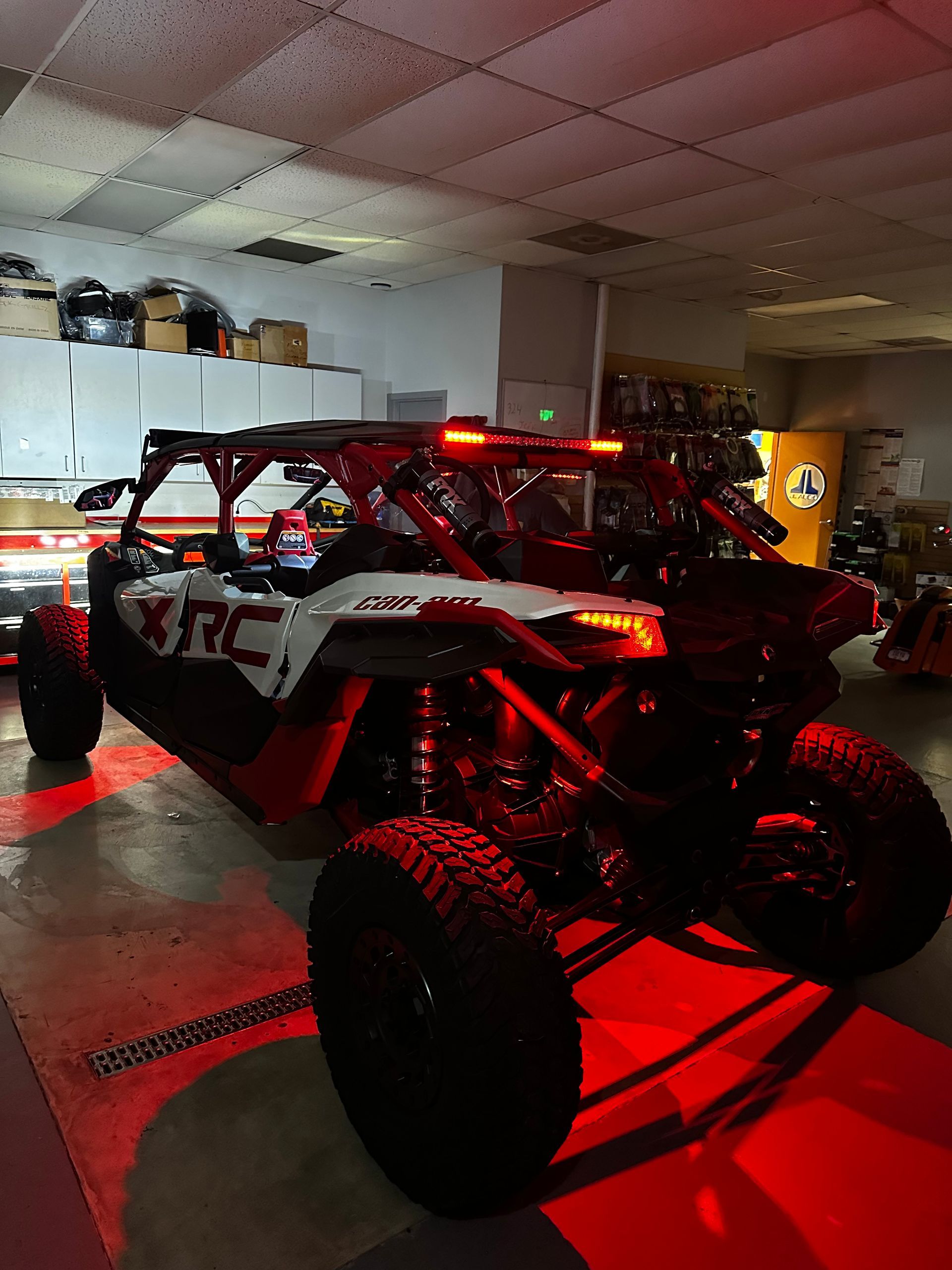 Red off-road dune buggy with LED lights parked in a garage, viewed from the rear side